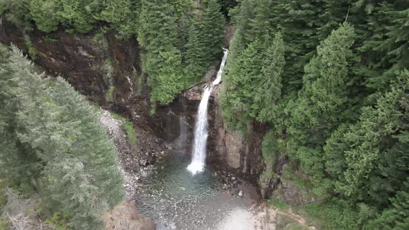 Aerial dolly in, A beautiful waterfall cascading through dense evergreen forest