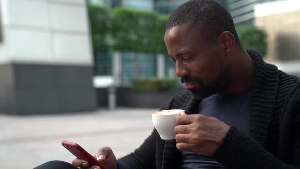 An African American Man Spends Time in a Cafe, Sitting on a Coffee Terrace, Drinking a Cup of Coffee