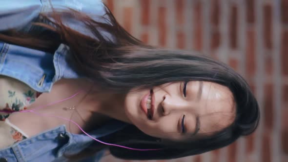 Vertical View of Beautiful Girl Listening To Music in Headphones and Smiling