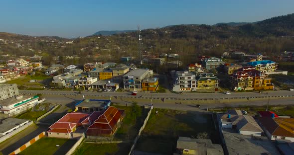 A city drone shot with road and houses. A tower is there of a telecom or internet. Clean and green t