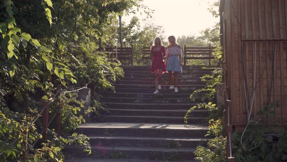 Two Attractive Beautiful Young Blond Women Blow Bubbles in the Park and are Happy on Sunset