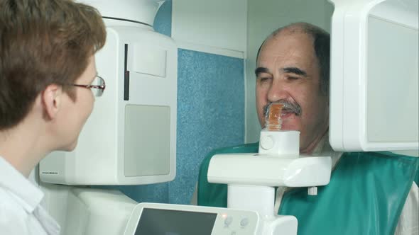 Dentist Talking To a Senior Patient Before Examination By Using Panoramic and Cephalometric X-Ray