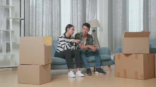 Young Asian Couple With Cardboard Boxes Discussing About The New House. They Move Into A New House