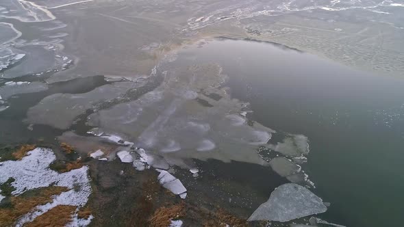 Aerial view looking down at ice melting over colorful lake