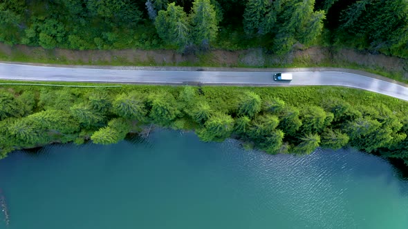 Aerial view of car driving through the fores and the lake on the side, Beautiful mountain road trip