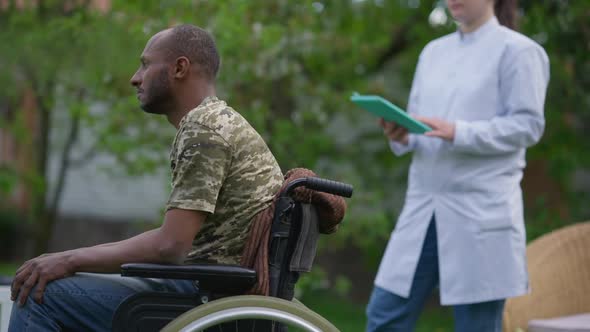Side View Portrait of Hopeless Desperate African American Disabled Veteran in Wheelchair Looking