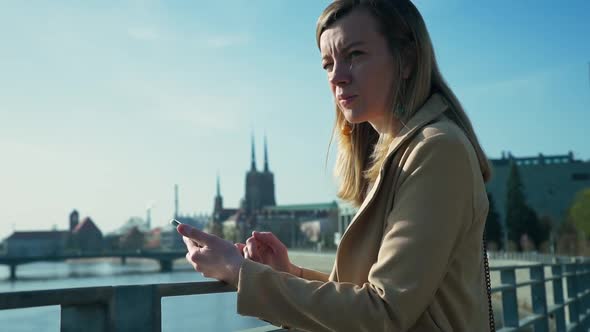 Woman at City Riverfront Use Smartphone