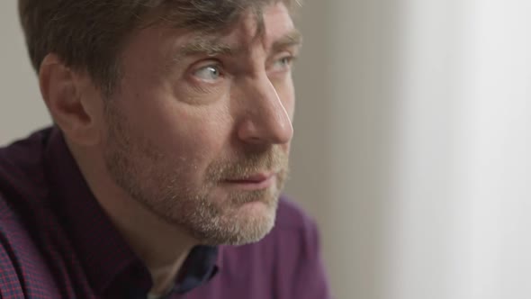 Closeup Face of Thoughtful Caucasian Man Sitting Indoors