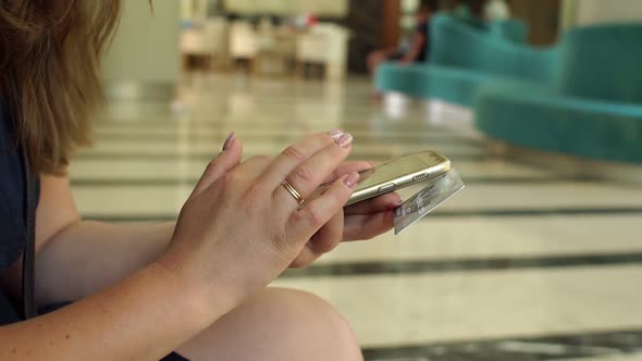 The Girl Pays the Bill By Phone and Credit Card in the Lobby of a Hotel