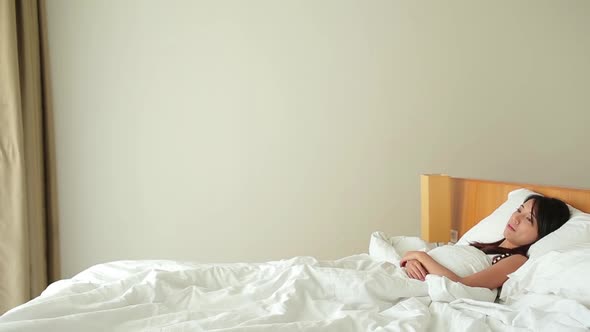 Woman laying down on bed and using mobile phone