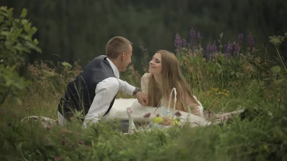 Groom with Bride Having a Picnic on a Mountain Hills. Wedding Couple. Family