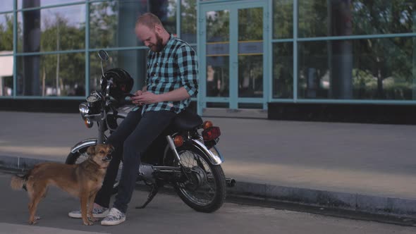 Male Motorcyclist with a Stray Dog on the Street