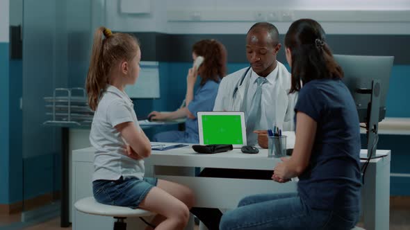 Tripod Shot of Pediatrician Showing Horizontal Green Screen on Tablet