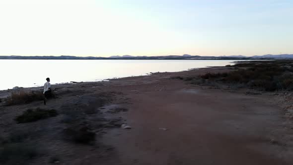 Man with the Guitar Running Along the Torrevieja Pink Lake at Sunset Alicante  Aerial Shot Slowmotin