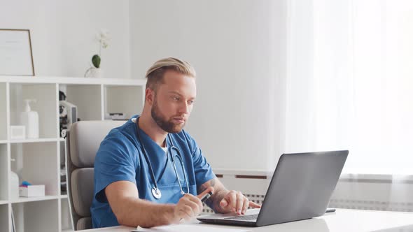 Professional medical doctor is working in hospital office using computer.