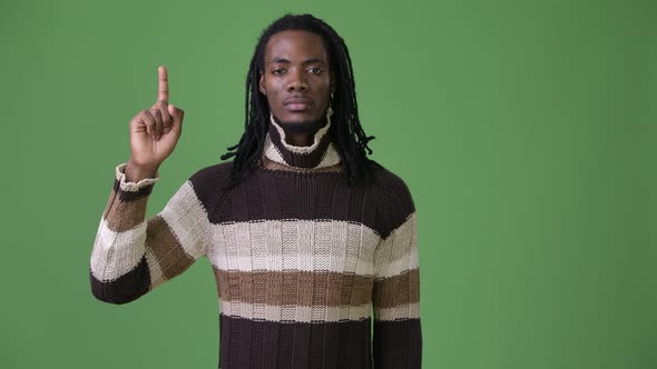 Young Handsome African Man with Dreadlocks Against Green Background