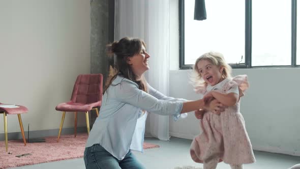 Mother Sits on the Carpet and Plays with Her Daughter the Child Runs Around