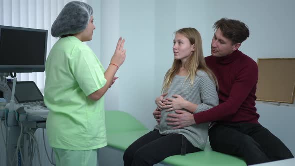 Young Pregnant Wife with Husband Learning Breathing As Doctor Gesturing Showing Exercise