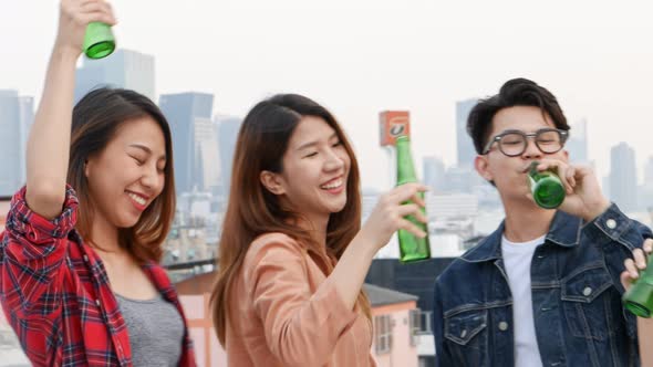 Group of Asian young people clinking bottles of beer party on the rooftop.