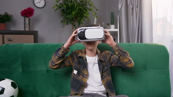 Boy which Sitting on Home Couch and Using Virtual Reality Headset to Play Video Game