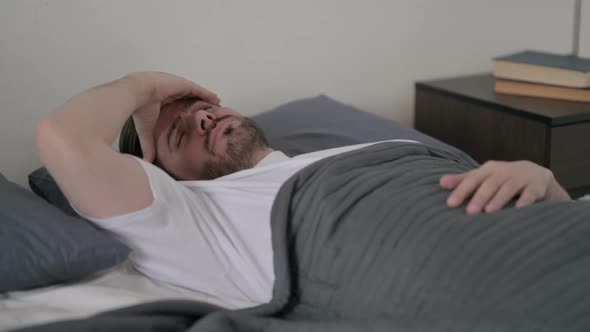 Young Man Having Headache While Sleeping in Bed