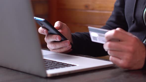 Businessman in a Black Hoodie Making Online Payment with Credit Card and Smartphone, Online Shopping