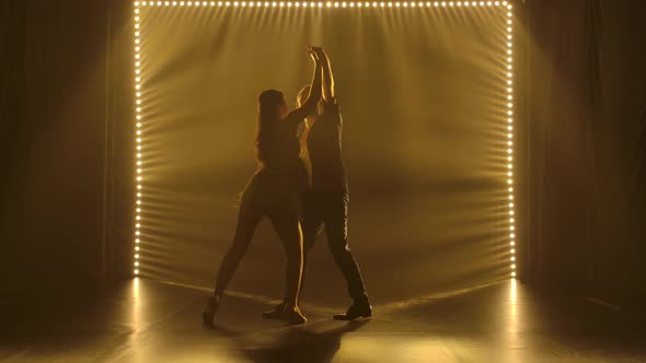 Young Couple Dancing Latin Music. Bachata, Merengue, Salsa. Shot in a Dark Studio with Neon Lights