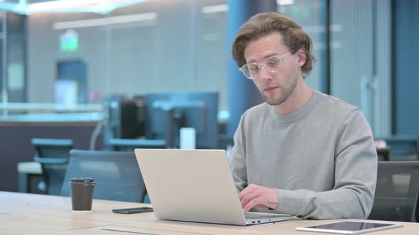 Young Businessman with Laptop Smiling at Camera