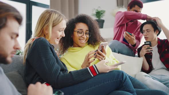 Happy Diverse Friends Group Using Devices Phones Laptop Digital Tablet Sit on Sofa Indoor Cheerful