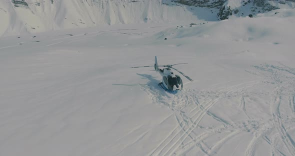 Aerial view, around Heliskiing helicopter and group of skiers, snowboarders in the winter mountains