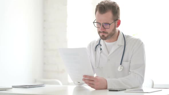 Doctor Celebrating Success While Reading Documents in Office