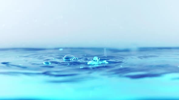 The clean water surface in slow motion fills the screen with water splashing shop the water drop and