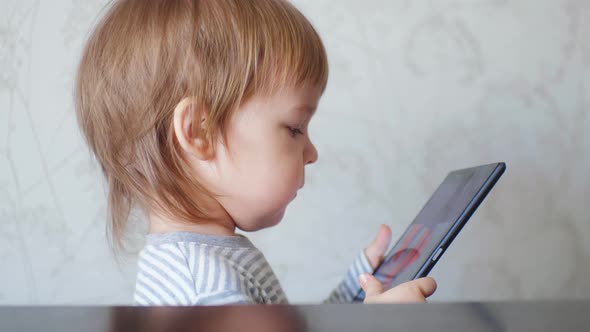 Side View Small Cute Boy Toddler Holding a Digital Tablet Watching Cartoons