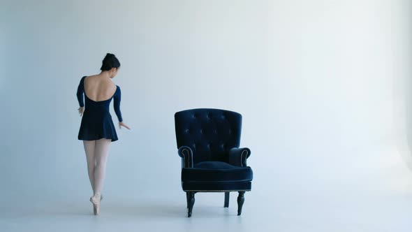 Young Asian Ballerina Dancing Near Antique Chair on White Background