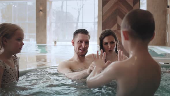 Hydrotherapy in Thermal Bath Family with Kids is Relaxing in Jacuzzi Dad Mom Daughter and Son