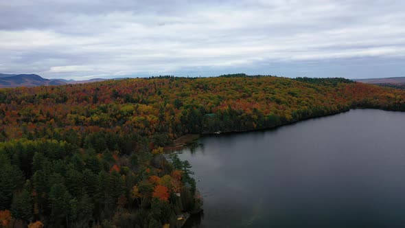 Aerial slide to left over shore of pond in northern maine in autumn