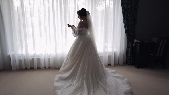 Smiling Bride in White Dress Staying at Home Bedroom Looking Sideways Wedding Preparations at Hotel