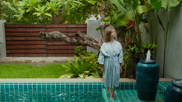 Attractive Woman in Bathrobe Walks Along Edge of Swimming Pool in Hotel Room