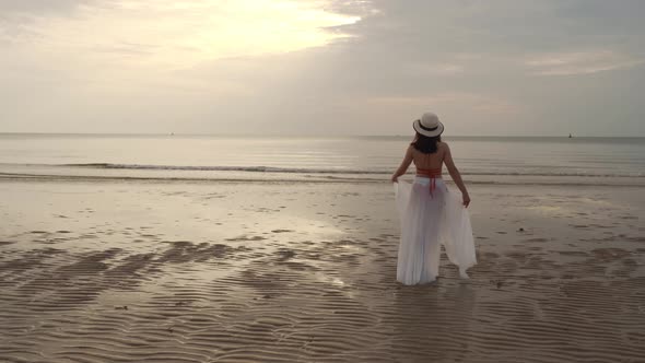 freedom woman in bikini walking with arms raised on the sea beach