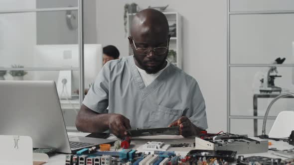 African American Engineer Working with Computer Components and Laptop