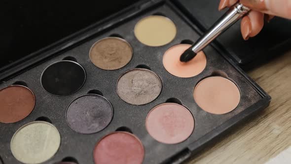 Close up of woman make up cosmetics palette with differents powder colors and a makeup brush in