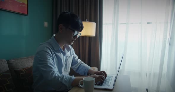 Young Attractive Asian Vietnam Man Busy Work Computer or Smart Tablet on Laptop at Home in Freelance