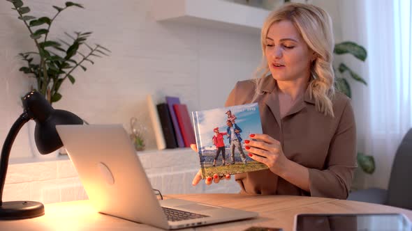 Close Up Young Woman Looking At Photobook Woman Presenting Photobook Near Laptop