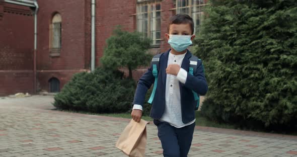 Crop View of Little Kid with Protective Medical Mask on His Face Walking and Looking To Camera