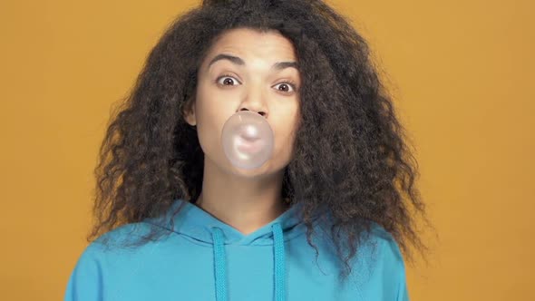 Portrait of afro american woman blowing bubble gum.