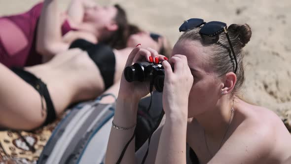 Beautiful Girl Looks Through Binoculars on the Beach