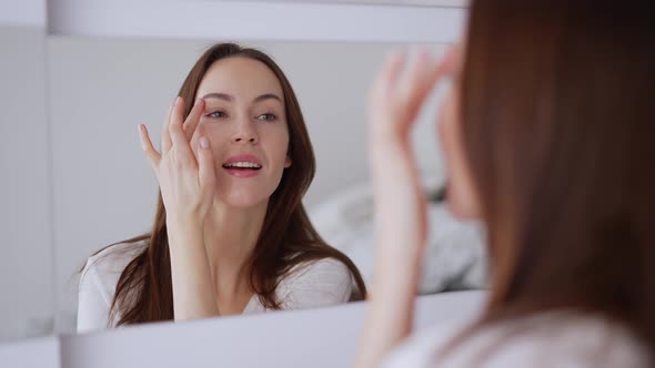 Glad Female Applying Concealer and Smiling