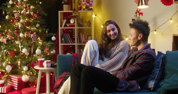 Young Man and Woman Talking Sitting on Sofa in Living Room