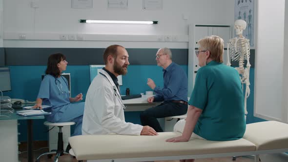 Male Doctor Consulting Senior Woman in Medical Cabinet