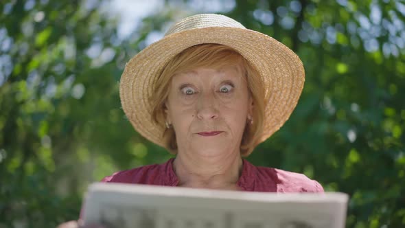 Dissatisfied Senior Woman Reading Newspaper Outdoors in Sunshine Throwing Away Paper in Slow Motion